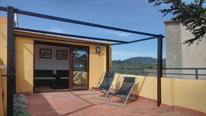 Ein Balkon mit zwei Liegestühlen, einer Schiebeglastür und Blick auf die Landschaft.