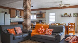 A living room with a grey sofa set, orange throw pillows, and a brick pillar.
