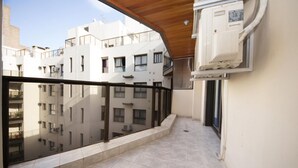 Een balkon met uitzicht op omliggende gebouwen, een betegelde vloer en een inbouwkast aan de muur.
