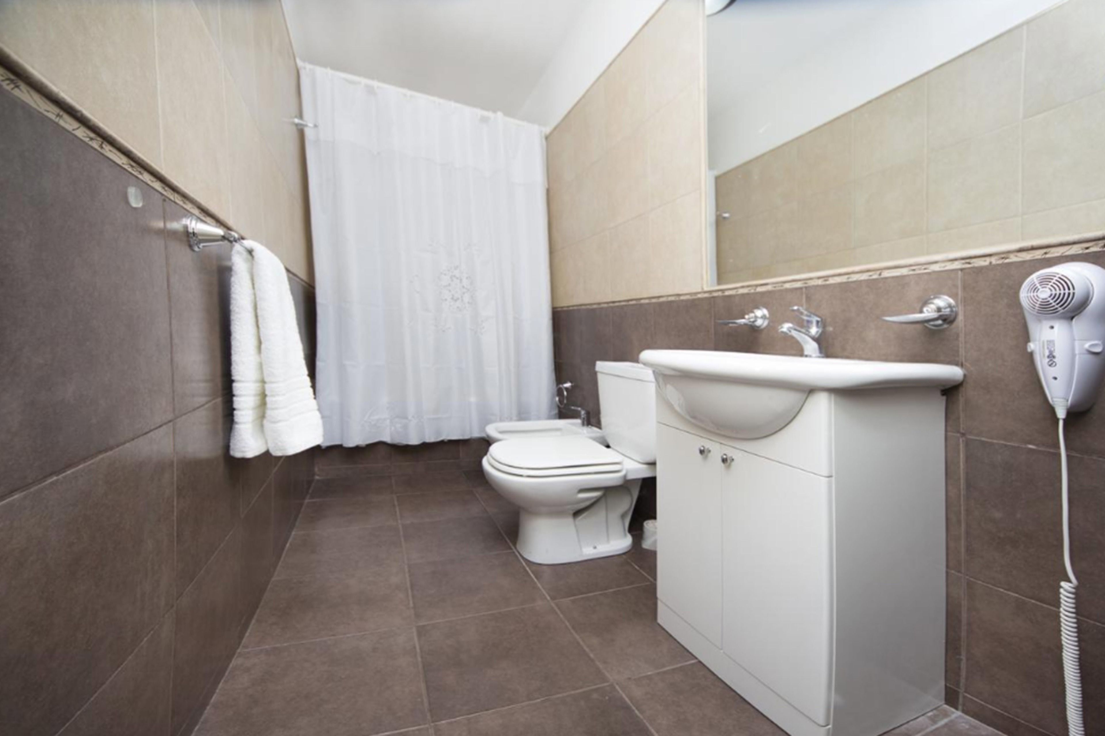 A bathroom with a toilet, sink, and hairdryer.