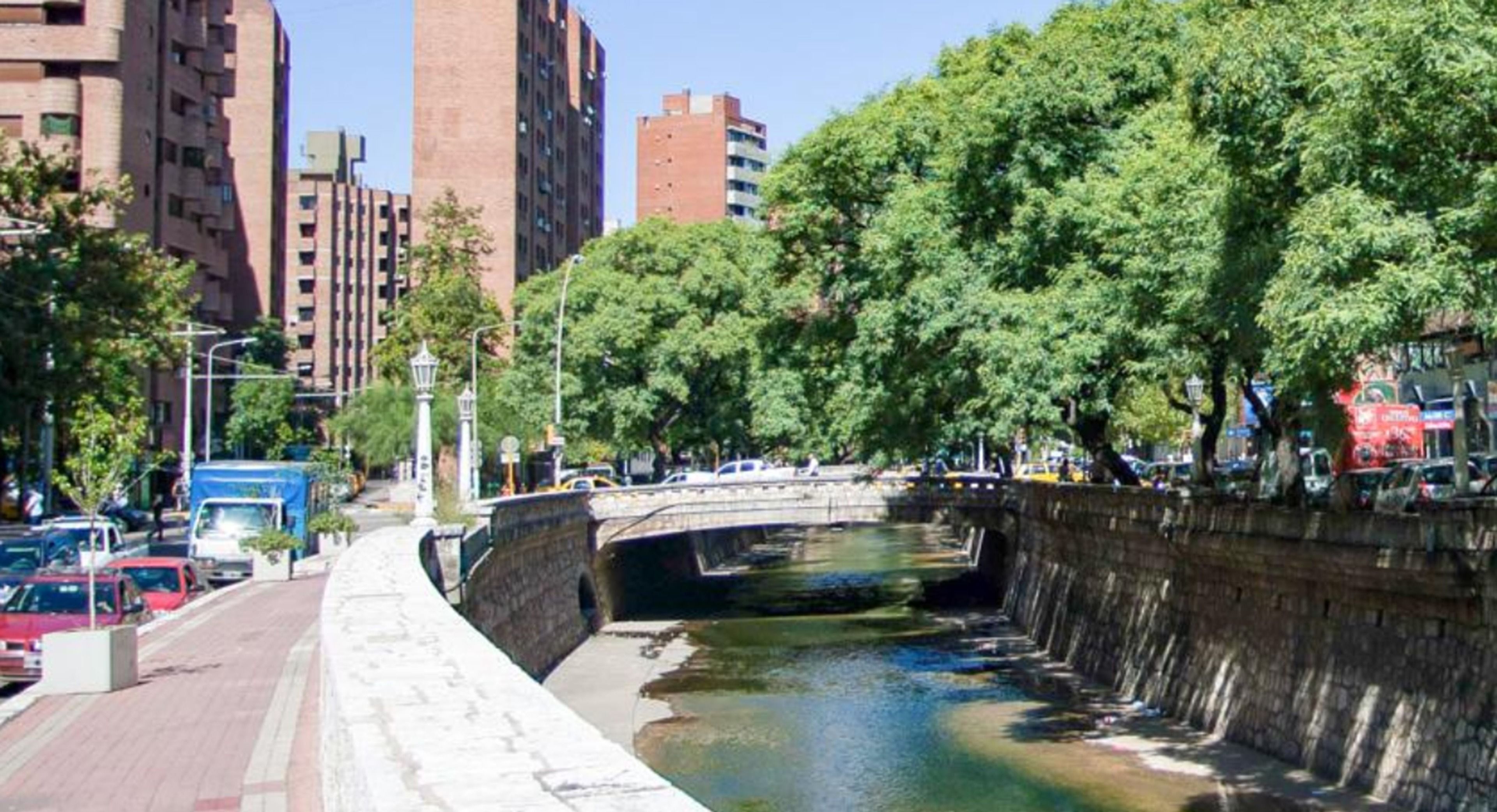 A canal with a stone wall on one side and a bridge crossing over it.