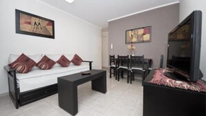 Un salon moderne comprenant un canapé, une table basse, une table à manger, des chaises et un téléviseur à écran plat.