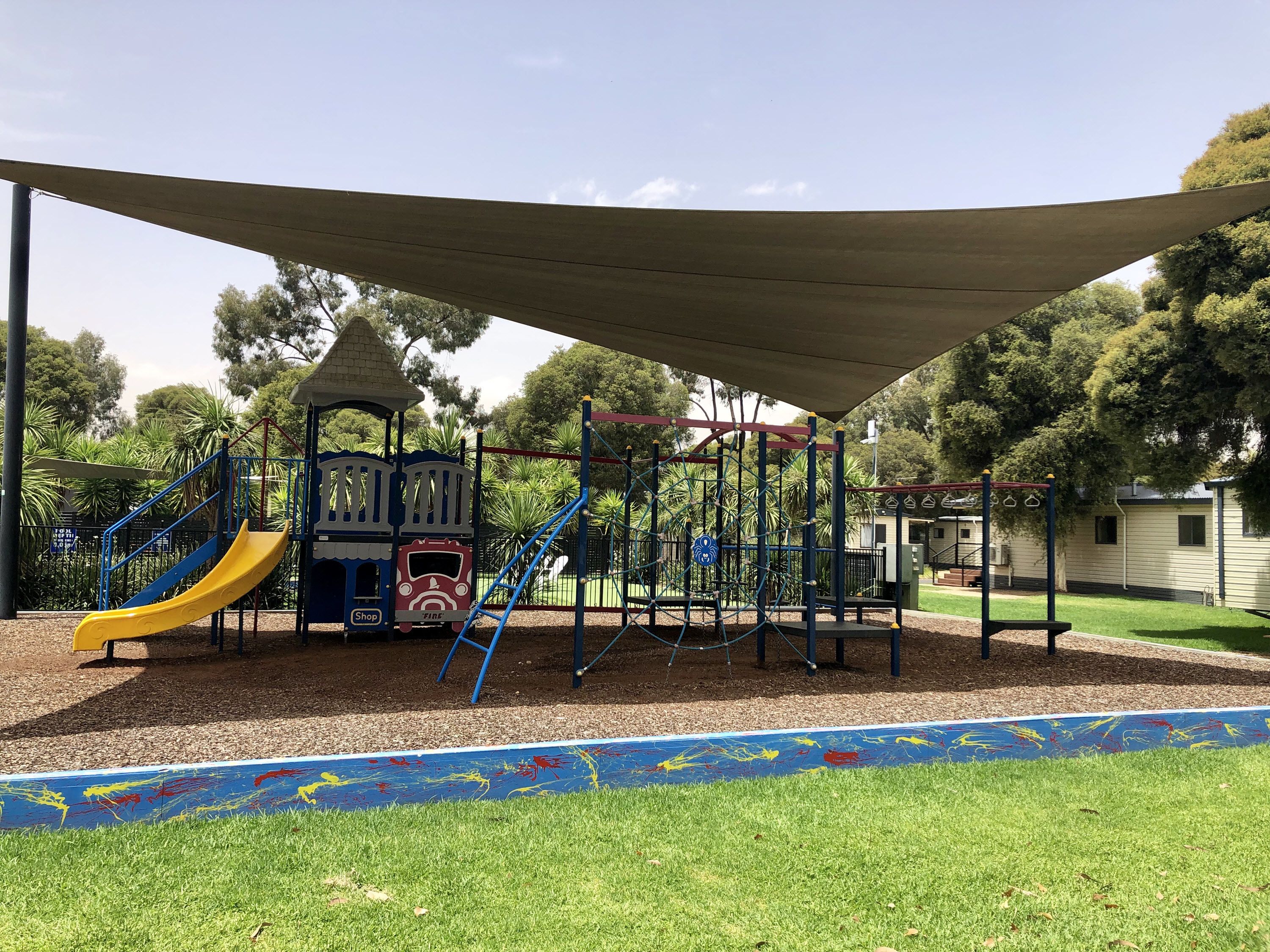 A playground with a slide, climbing structures, and a covered area.