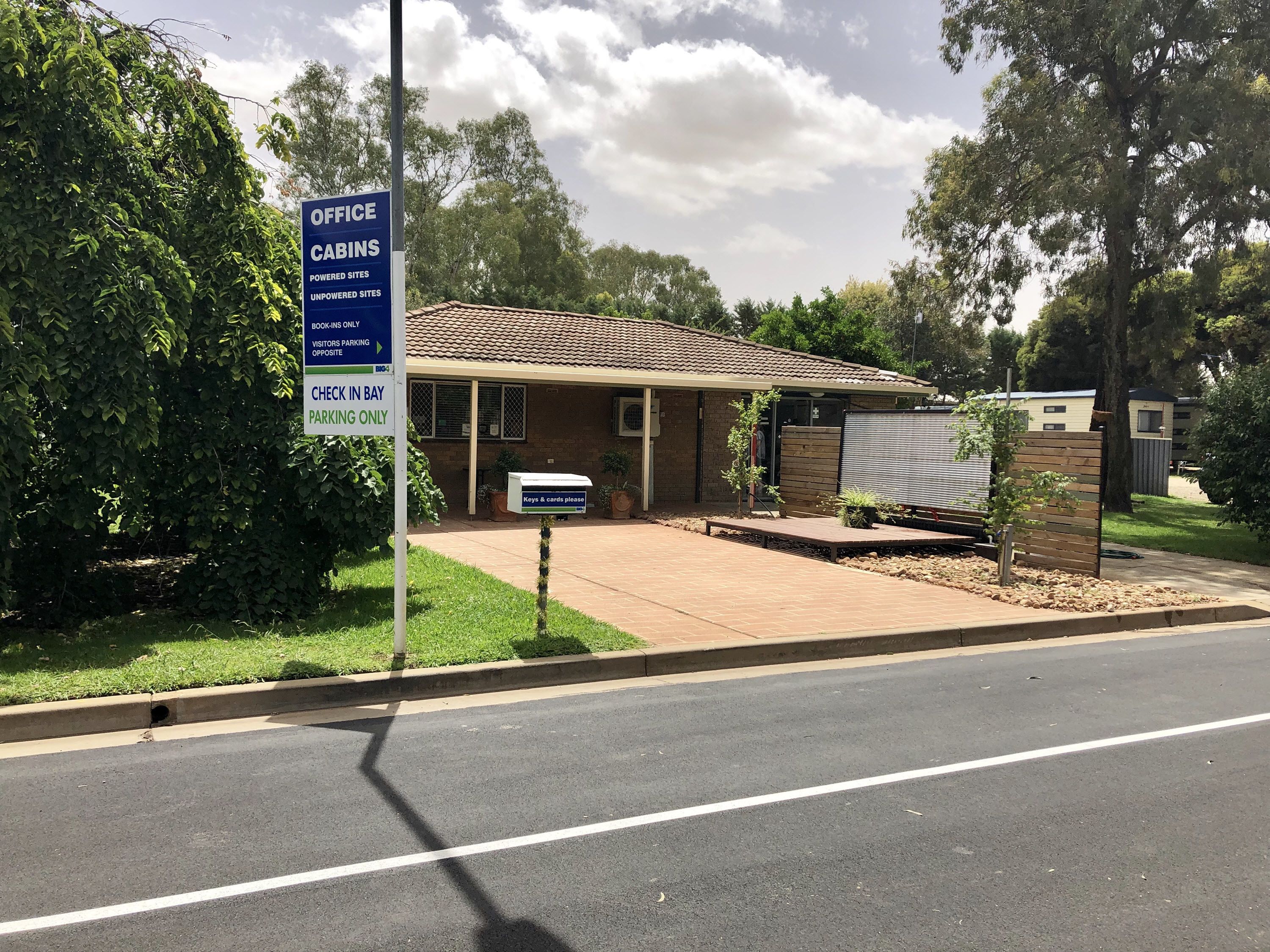 A building labeled "Office Cabins Powered Sites Unpowered Sites" with a sign indicating "Check in Bay Parking Only."