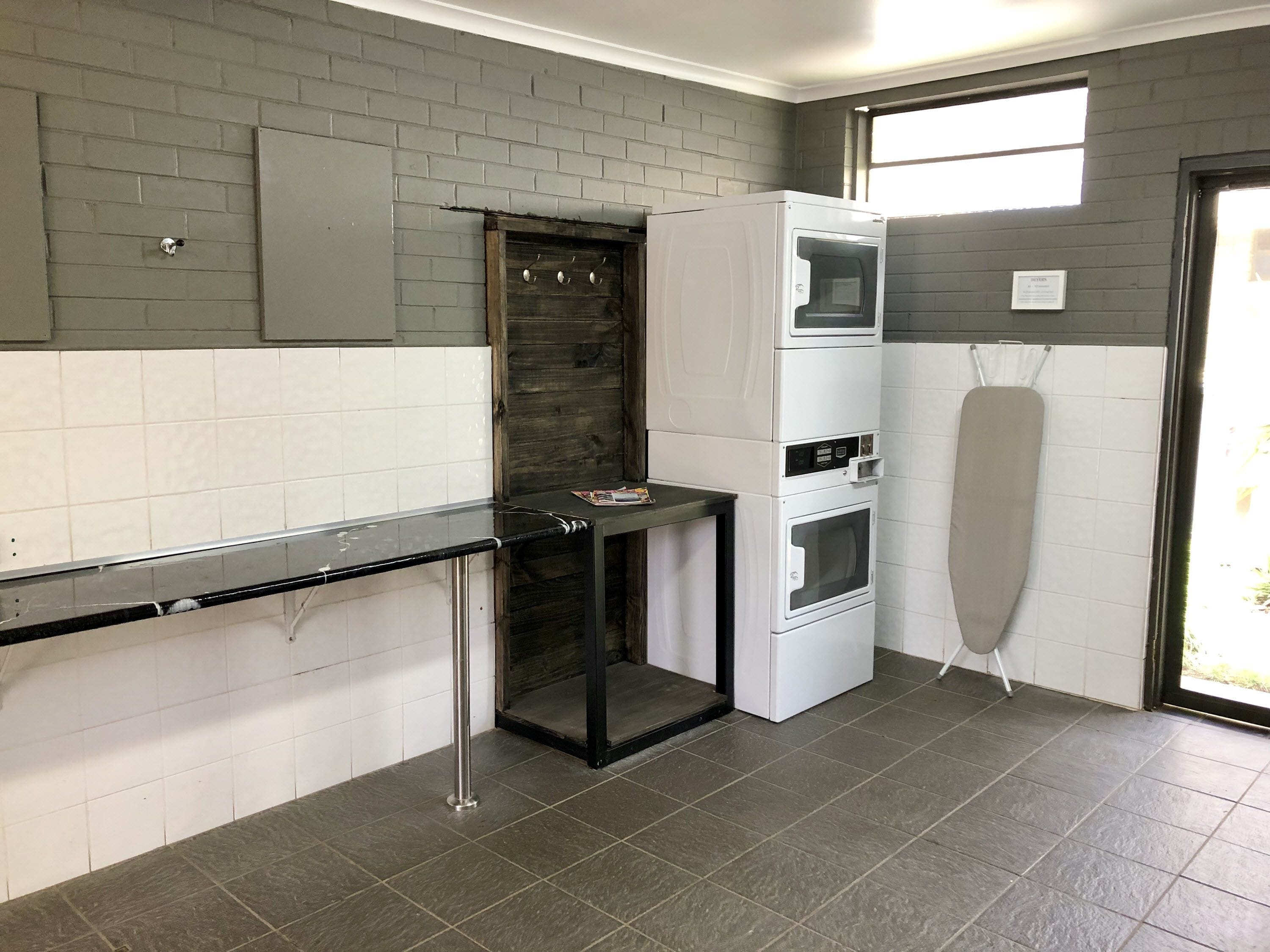 Una cocina compacta con encimera negra, horno empotrado y microondas.