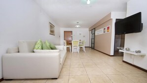 A modern living room with a white sofa, green pillows, a dining table with chairs, and a flat-screen TV mounted on the wall. - Fragueiro Flat BU6 (Córdoba)