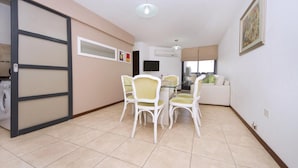 A compact living space with a dining area, a sofa, a washing machine, and a TV. - Fragueiro Flat BU6 (Córdoba)