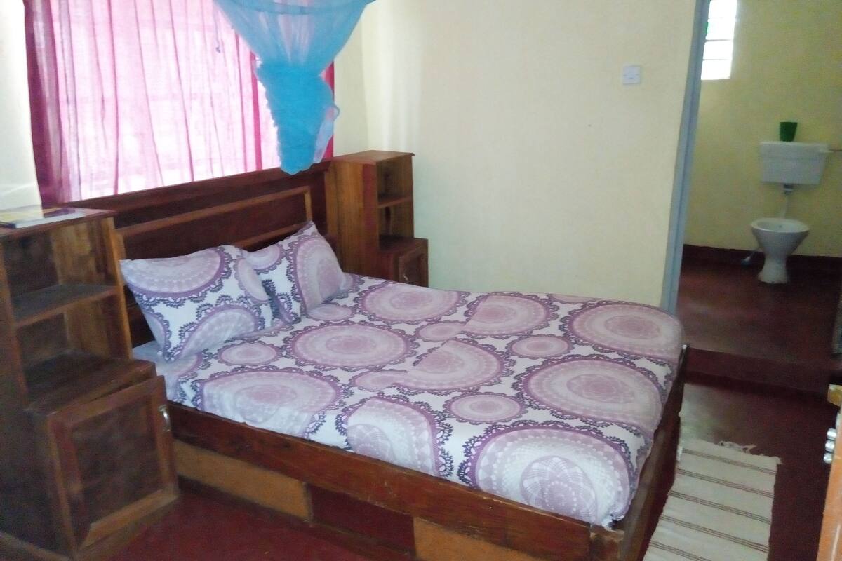 A bed with a patterned bedspread, wooden headboard, and bedside tables.
