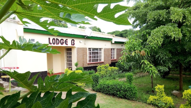 A building labeled 'Lodge B' with a green roof, surrounded by greenery and a gravel path. - Lodge B Mawira (Liwonde)