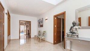 A hallway with a wooden door, a statue on a console table, and two chairs. - Casa Las Vías (Petra, Mallorca)