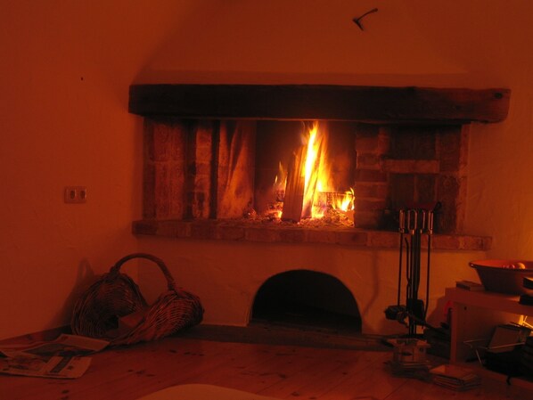A fireplace with a fire burning inside, a basket, and some items on the floor.