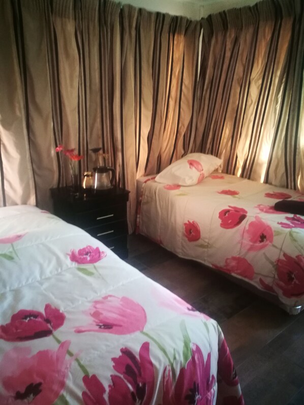 A bedroom with two beds, a nightstand, and curtains.