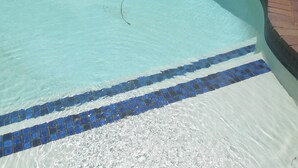 A swimming pool with clear blue water and a tiled edge. - Naisar Royal White Apartment (Germiston)