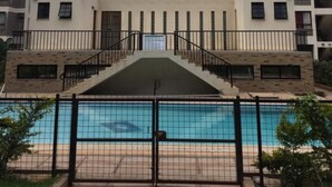 A multi-story building with balconies and a swimming pool in front. - Amani homestay (Syokimau)