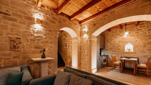 A cozy living room with a stone wall, wooden beams, a sofa, and a dining area with chairs and a table. - Stone villa with pool & fantastic sea views (with special autumn offers) (Rethymnon)