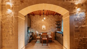A stone-walled kitchen with a wooden table and chairs, under an arched ceiling with exposed beams. - Stone villa with pool & fantastic sea views (with special autumn offers) (Rethymnon)