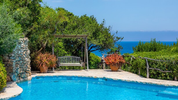 A pool with a wooden deck, a stone wall, and a bench. - Finca by the sea (Colonia de Sant Pere)
