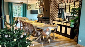 Zona pranzo con albero di Natale, camino e angolo cottura caratterizzato da una parete a scacchi e uno specchio.