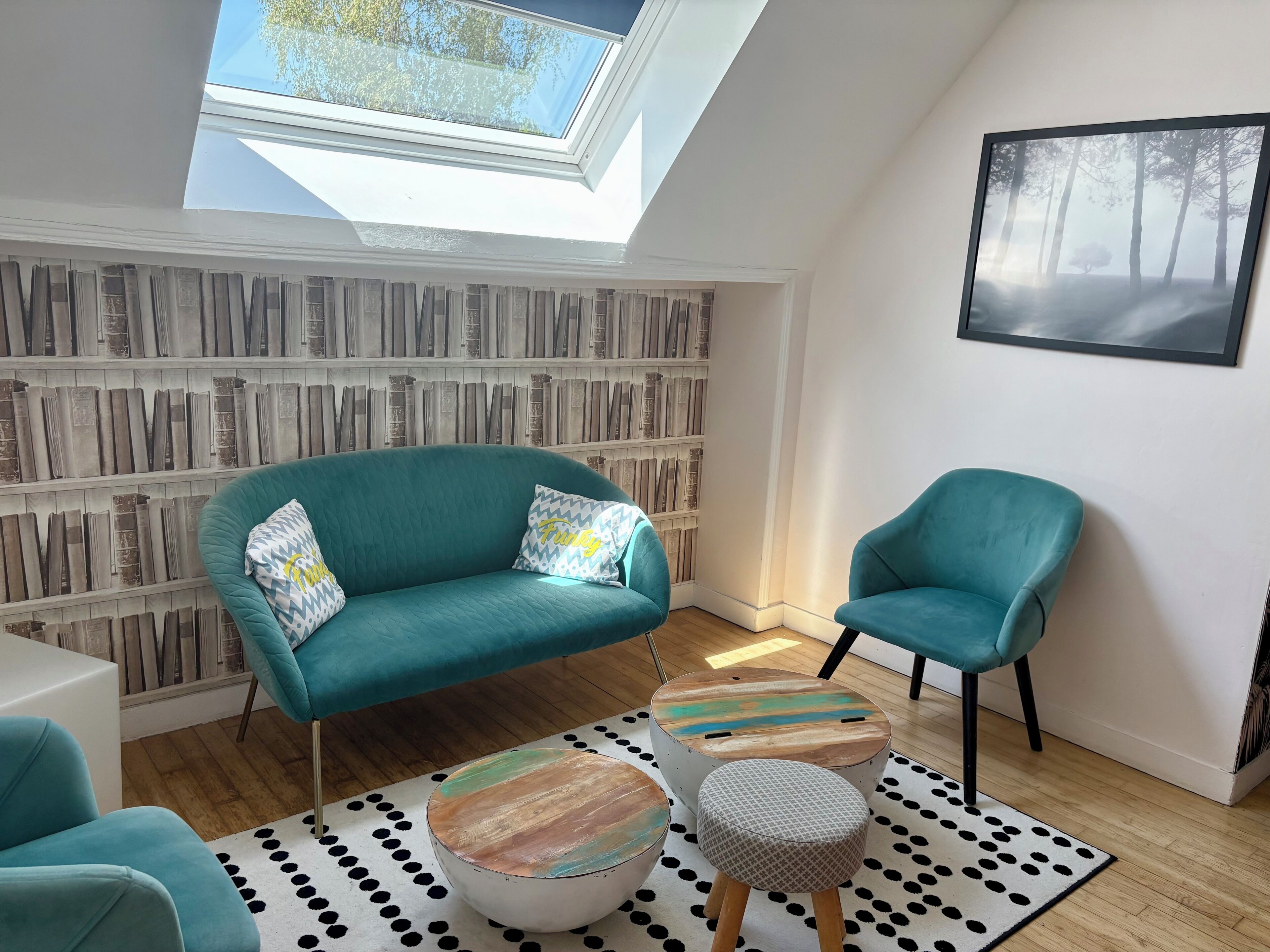 A modern living room with a teal sofa, a matching armchair, and a coffee table with a polka dot rug.