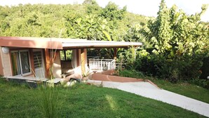 A house with a covered porch, a concrete pathway leading to the entrance, and a lush green garden.