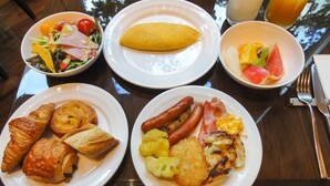 Uma mesa de café da manhã com pratos de comida, incluindo croissants, linguiças e uma salada.