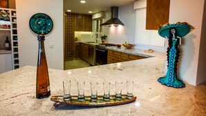 A kitchen with a marble countertop, a bottle, and a decorative plate. - STUNNING 3 BR & 3BA SOUTH SHORE BEACHFRONT RESIDENCE! (Puerto Vallarta)