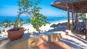 A beachside restaurant with a thatched roof, outdoor seating, and a view of the ocean. - STUNNING 3 BR & 3BA SOUTH SHORE BEACHFRONT RESIDENCE! (Puerto Vallarta)