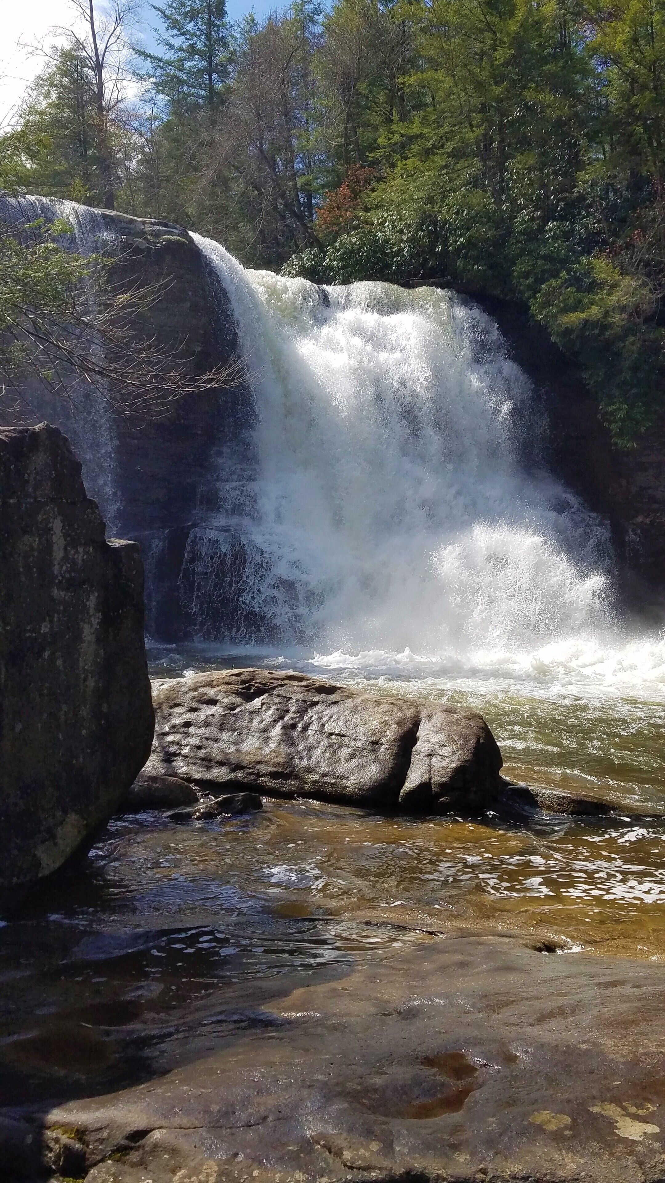 Uma cascata caindo sobre rochas em uma área arborizada.