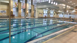 Una piscina interior con varias pistas de natación, una silla de salvavidas y un reloj en la pared.