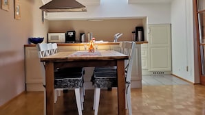 A compact kitchen with a dining area, a built-in microwave, a coffee maker, and a stainless steel range hood. - Landhaus Mitsche, apartment panoramic view in a quiet, sunny position (Radnig)