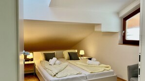 A bedroom with a large bed, two bedside tables with lamps, a window, and a door. - Landhaus Mitsche, apartment panoramic view in a quiet, sunny position (Radnig)