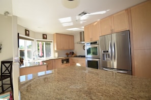 A modern kitchen with granite countertops, stainless steel appliances, and wooden cabinets.