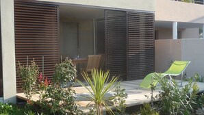 A modern outdoor patio with a wooden deck, a green chair, and a table.