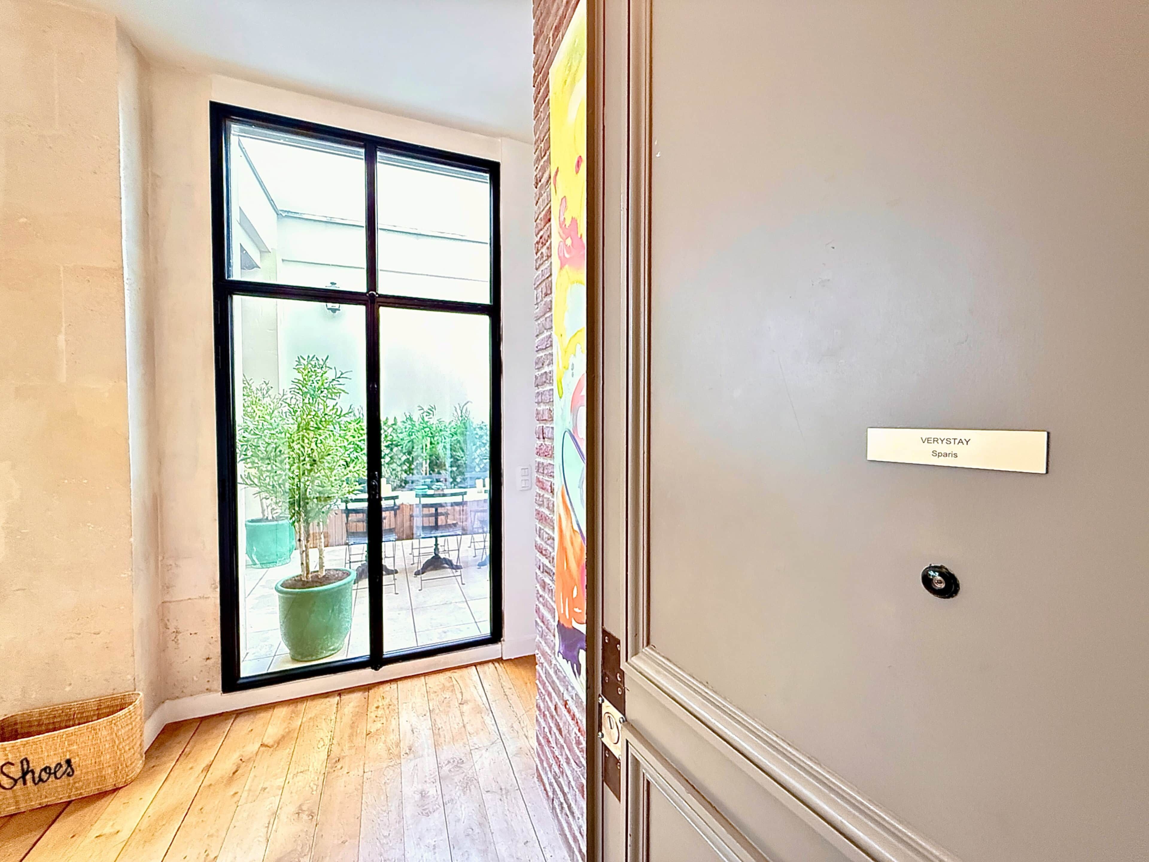 A room with a large sliding glass door leading to an outdoor area with potted plants and a seating area.
