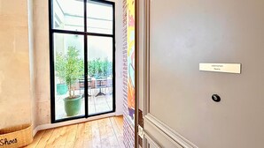 A room with a large sliding glass door leading to an outdoor area with potted plants and a seating area. - Sparissimo, 6 Br / 4 Ba, 14 ppl, 220 m² (Paris)