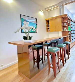 Eine moderne Küche mit einer Holztresen, Barhocker, einer Topfpflanze mit Orchidee und einem Bücherregal mit Büchern und Dekoration.