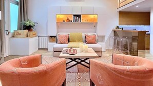 A modern living room with a sofa, two armchairs, a coffee table, and a kitchen area with bar stools. - Sparissimo, 6 Br / 4 Ba, 14 ppl, 220 m² (Paris)
