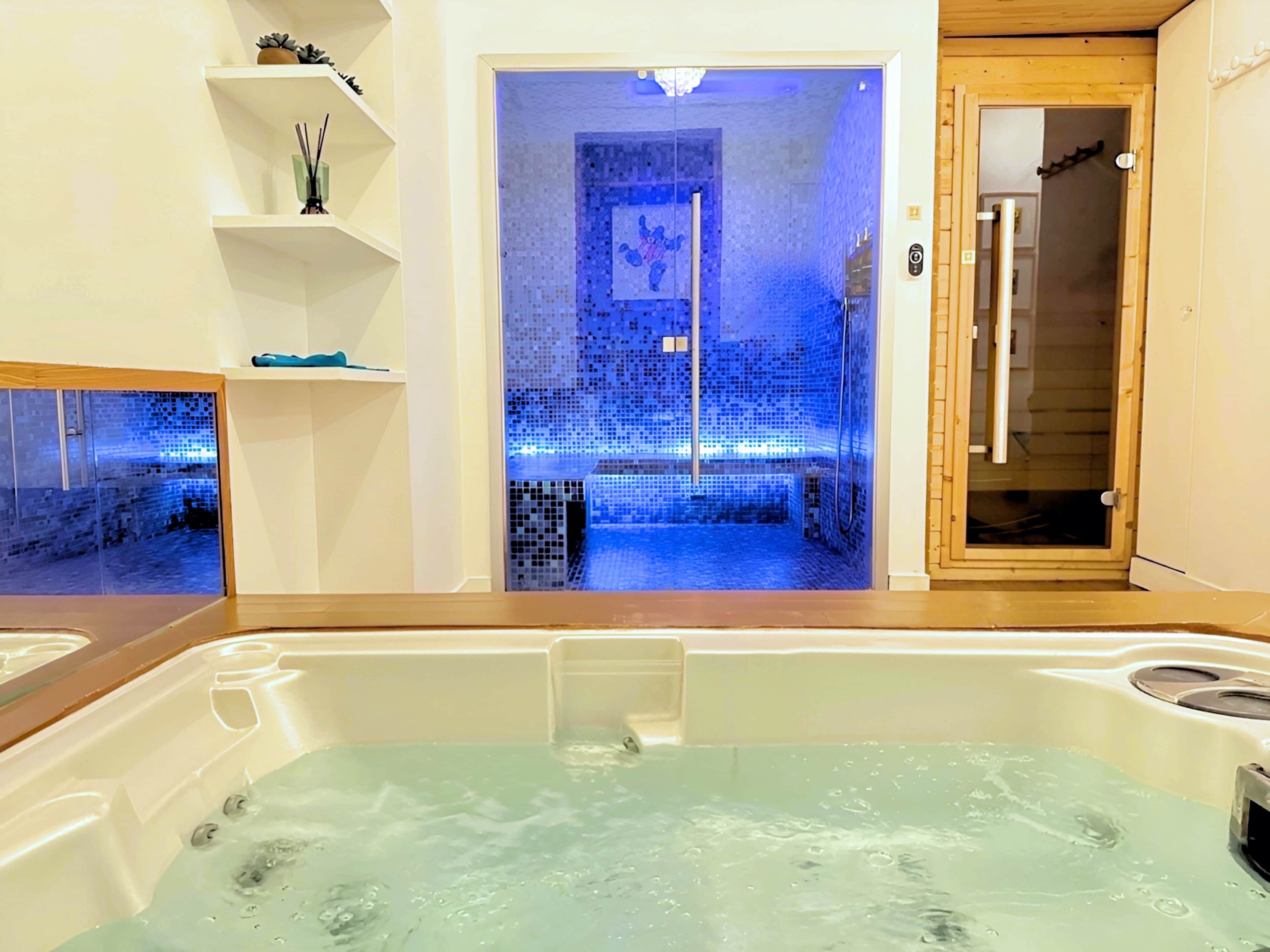 A bathroom with a bathtub, a shower area with mosaic tiles, and a wooden door.