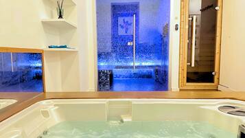 A bathroom with a bathtub, a shower area with mosaic tiles, and a wooden door.