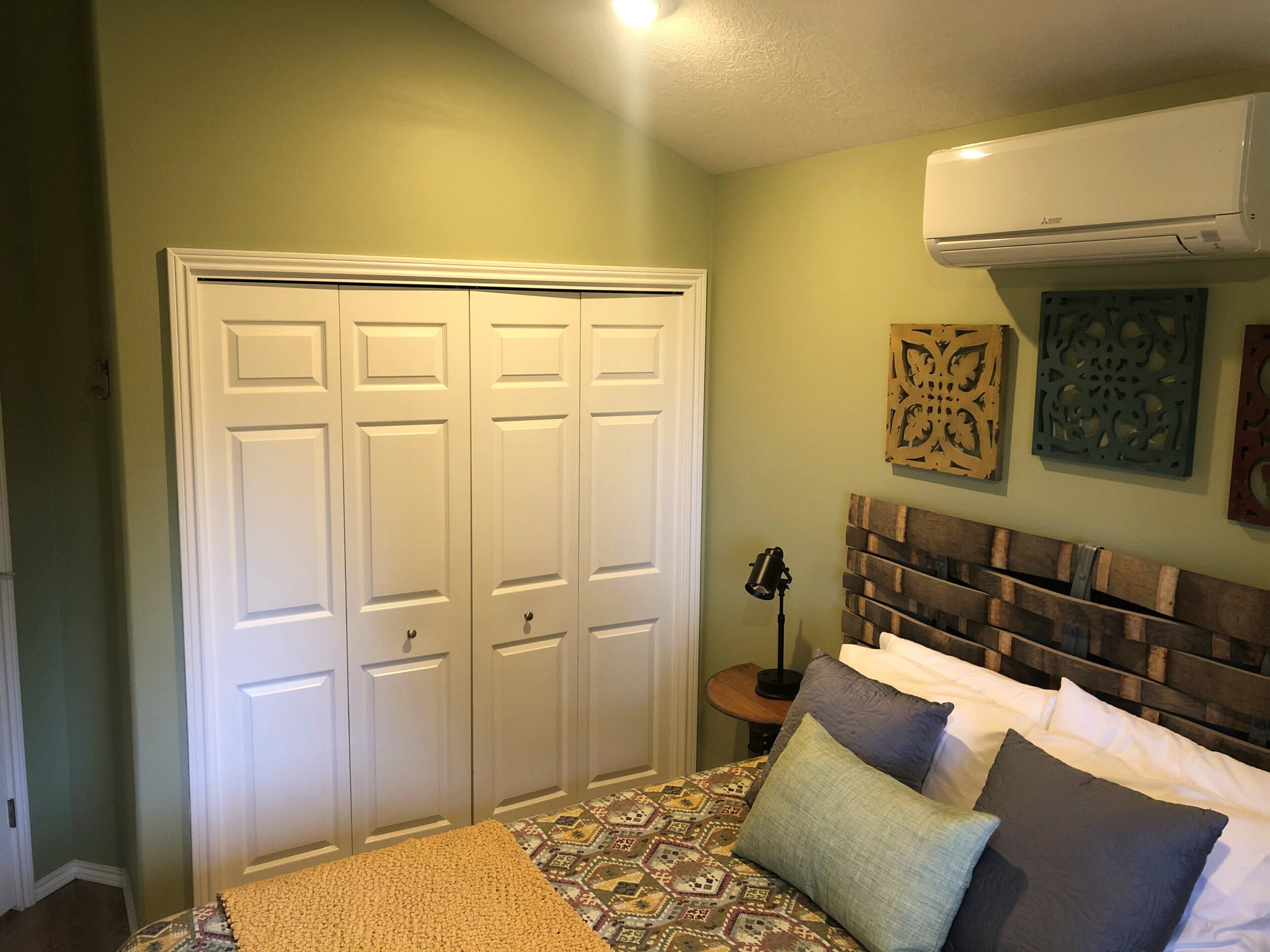 Une chambre à coucher comprenant un lit, une armoire et un appareil de climatisation.