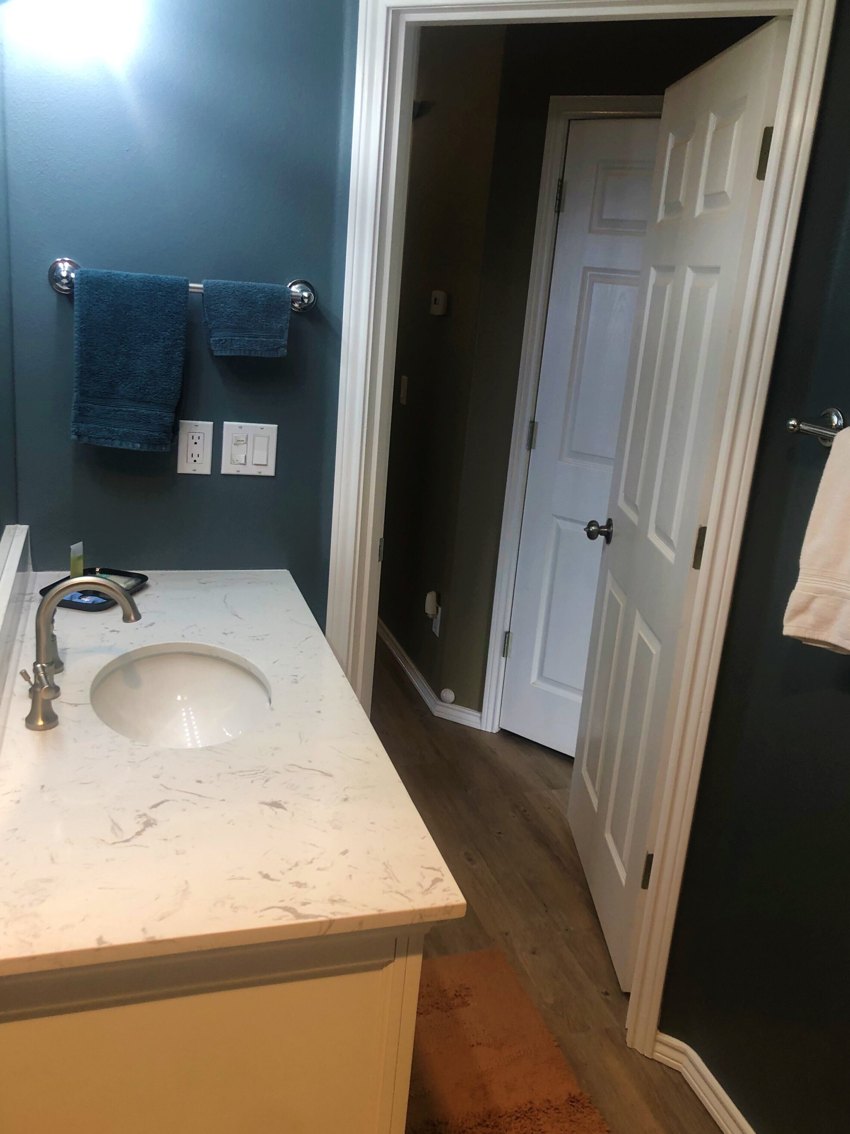 Une salle de bain avec un lavabo blanc, des serviettes bleues et une porte blanche.