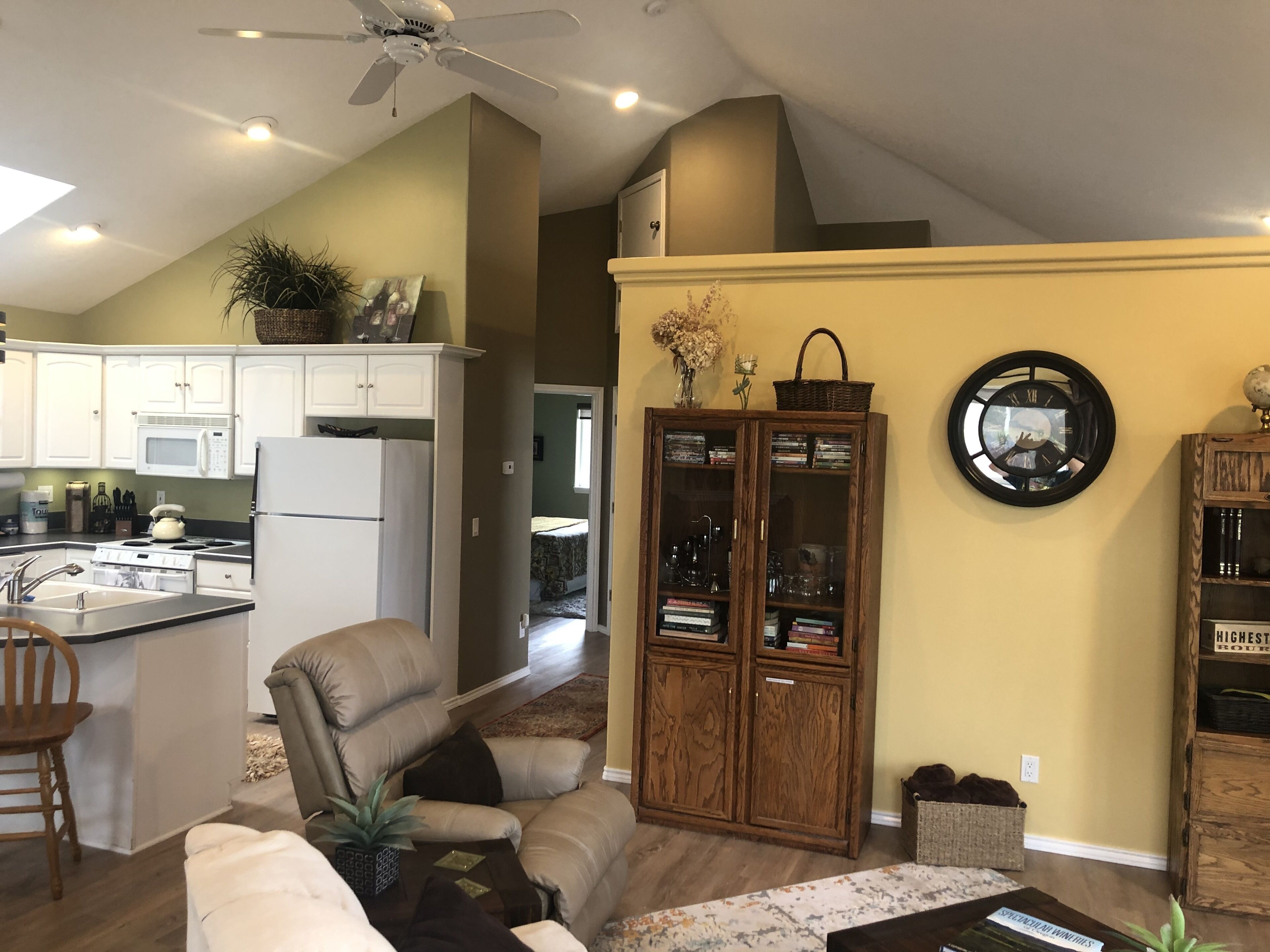 A spacious living room with a large window, a kitchen with white cabinets, and a dining area.