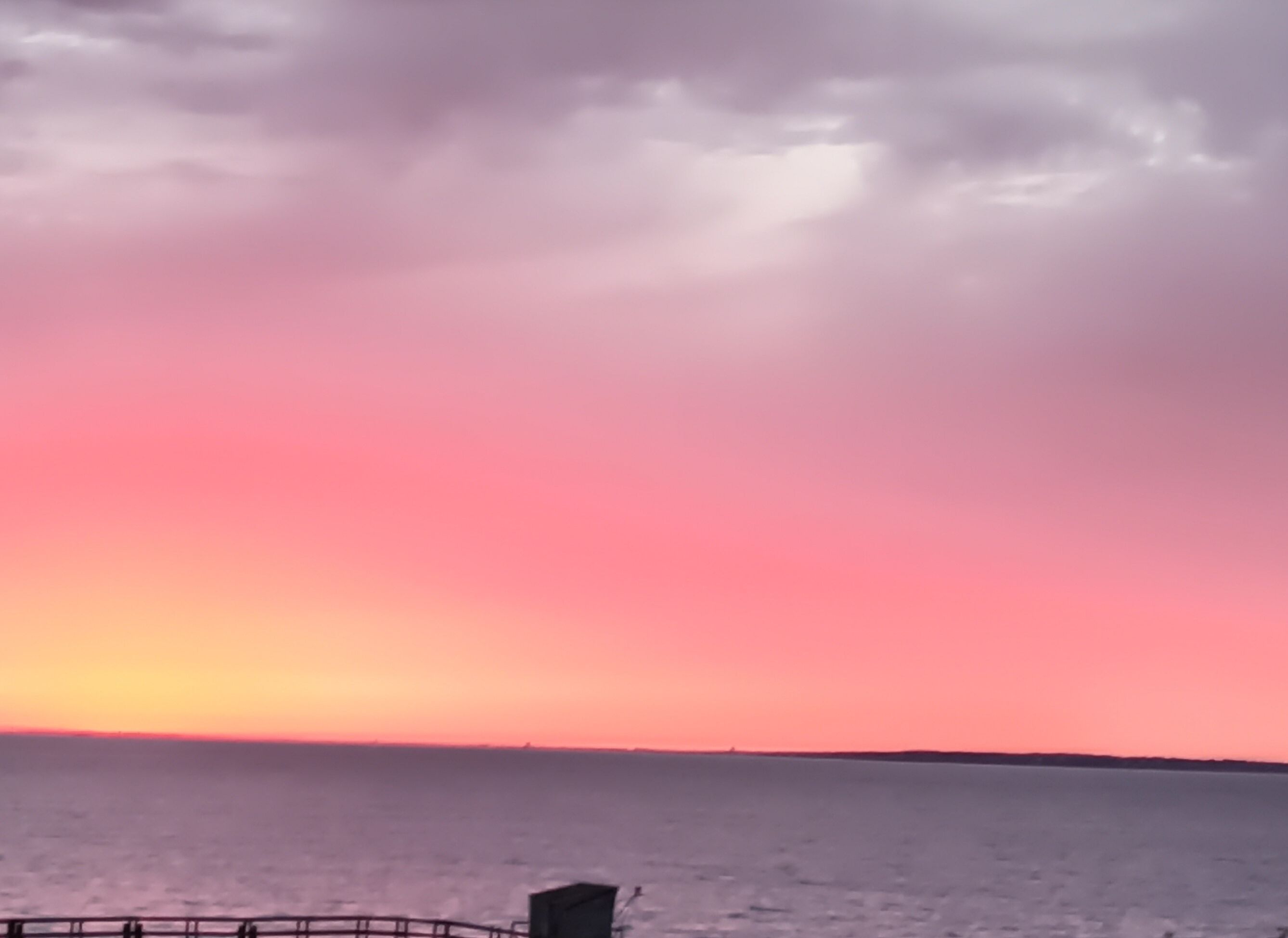 Un atardecer sobre un mar tranquilo con un horizonte lejano.