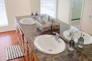 Ein Badezimmer mit zwei Waschbecken, einem Spiegel und einem Holzlagerflächen-Möbel.