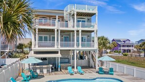 A two-story building with a swimming pool, outdoor seating, and a covered patio area. - " 'Til Next Time!" Pool w/Opt. Heat, Hot Tub, Tiki Bar, Elevator, Crow's Nest (Holden Beach)
