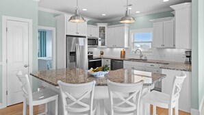 A modern kitchen with granite countertops, white cabinetry, and pendant lighting. - " 'Til Next Time!" Pool w/Opt. Heat, Hot Tub, Tiki Bar, Elevator, Crow's Nest (Holden Beach)