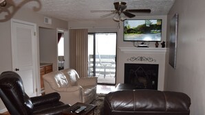 A living room with a fireplace, a television mounted above it, and a view to the outside.