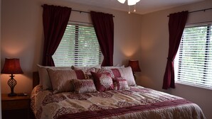A bedroom with a large bed, two bedside lamps, and a window with curtains.