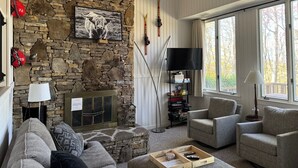 Una sala de estar acogedora con chimenea de piedra, asientos cómodos, un televisor de pantalla plana y un letrero que dice 'RELAX'.
