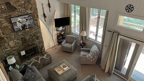 Una sala de estar acogedora con chimenea de piedra, un televisor de pantalla plana y un cartel que dice 'RELAX'.
